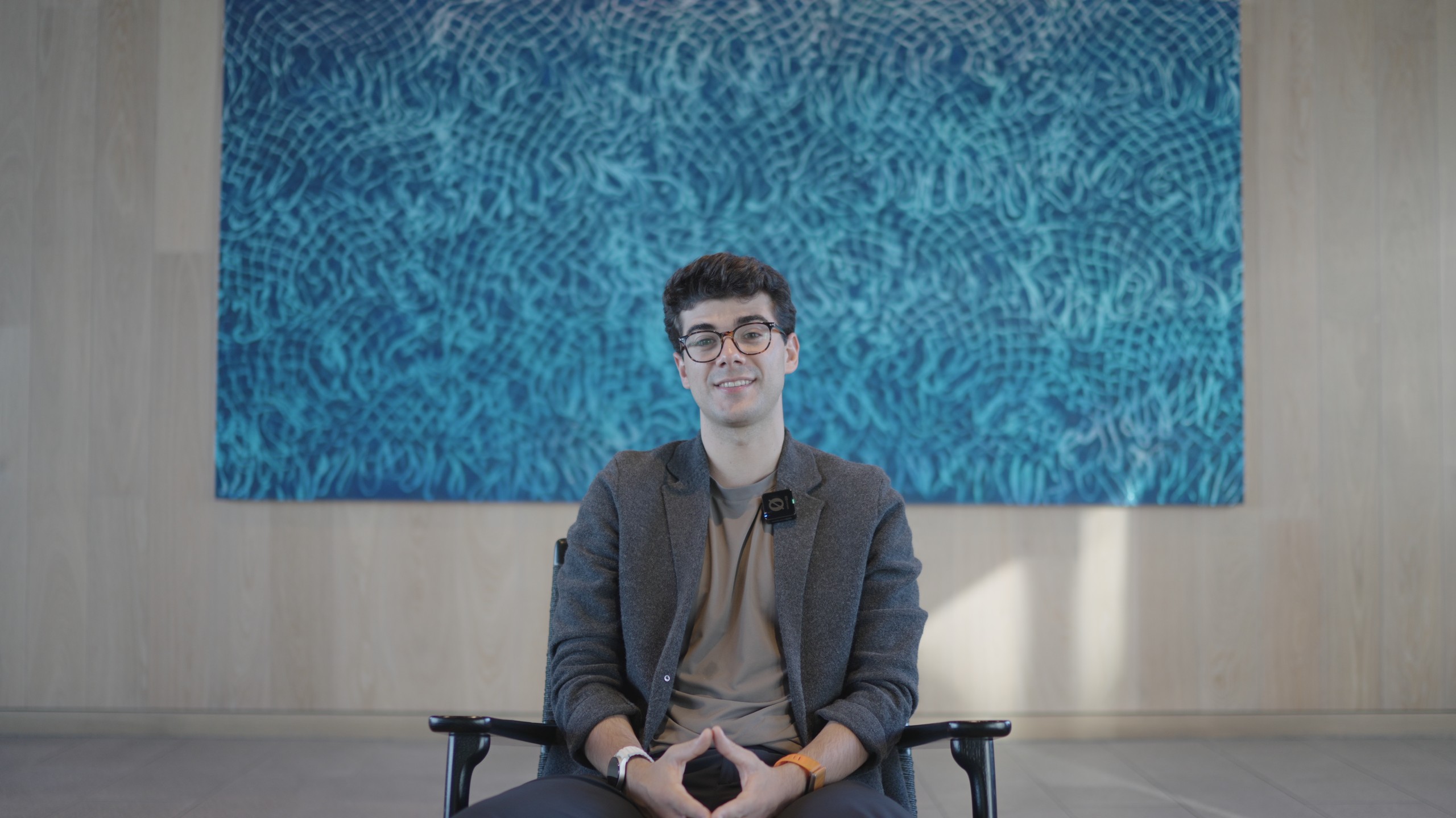 Thrad CEO Andrea Tortella seated in front of a large blue painting during a FogLine Visuals shoot in San Francisco