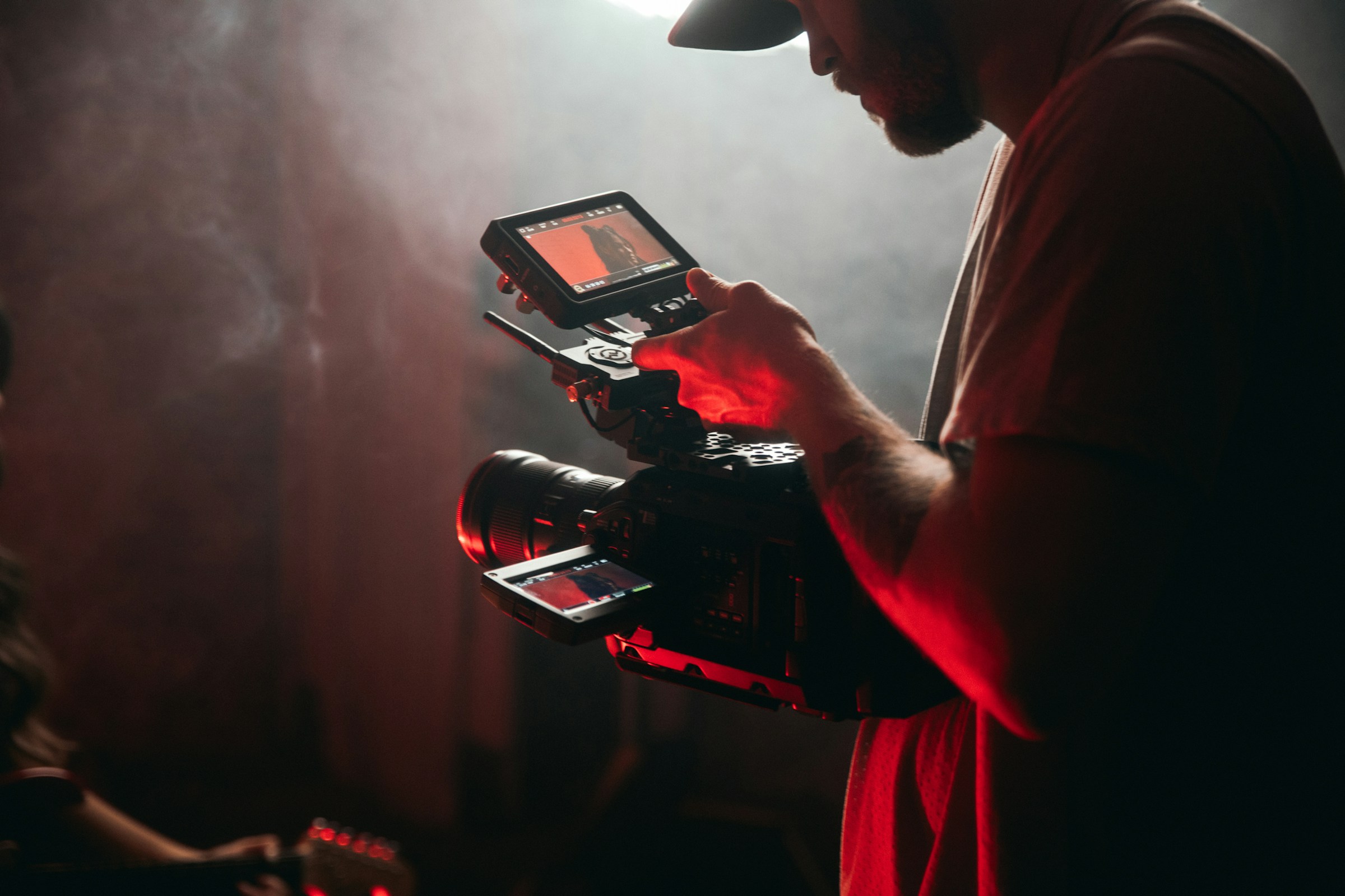 Camera operator reviewing a monitor in a red-lit studio