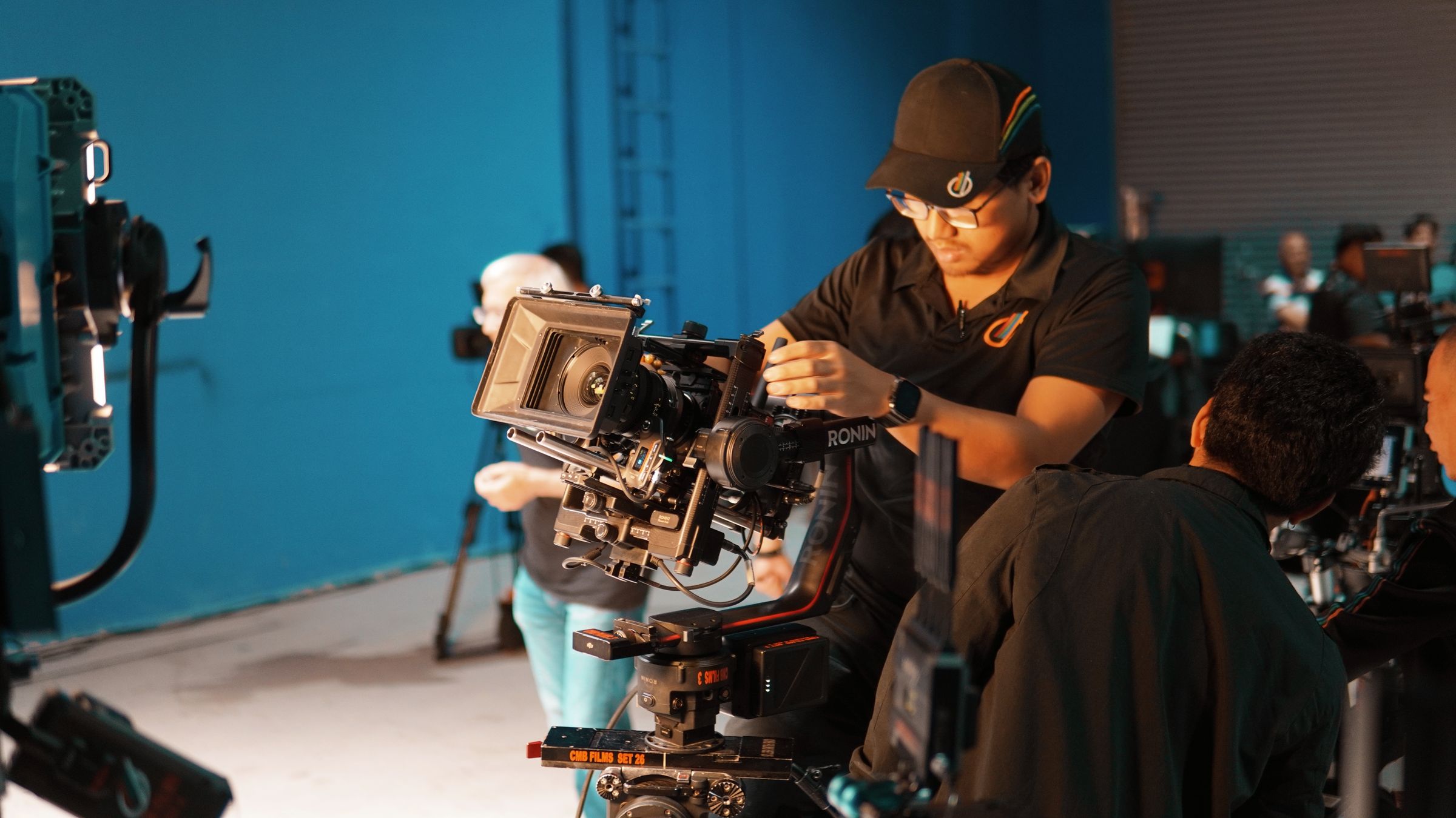 Cinema camera rig and crew on a teal-lit set