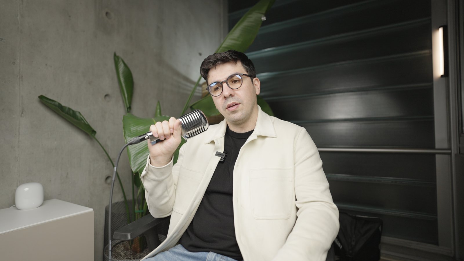 Artin Bogdanov, CEO of SUN, vintage mic against the dark wall, filmed by FogLine Visuals at its SoMa studio in San Francisco